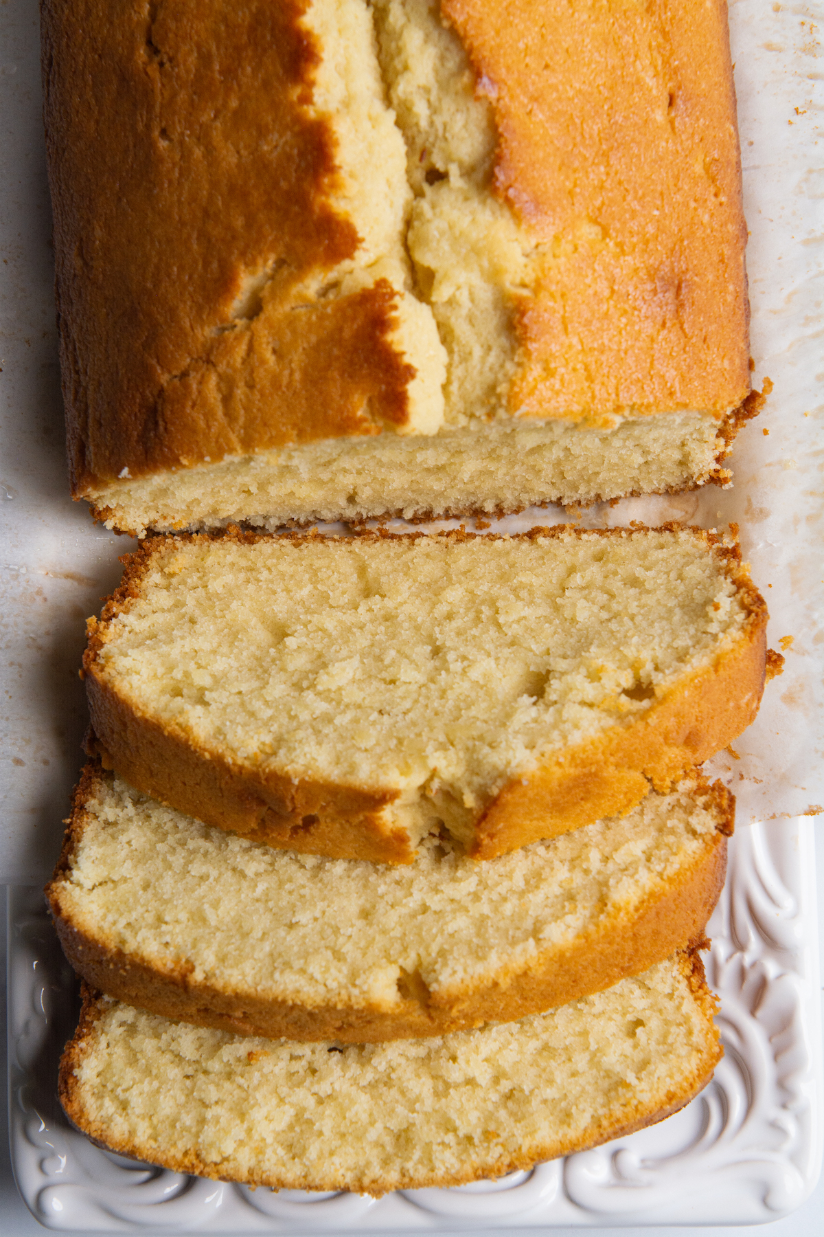 A loaf of pound cake cut into three slices on a serving platter.