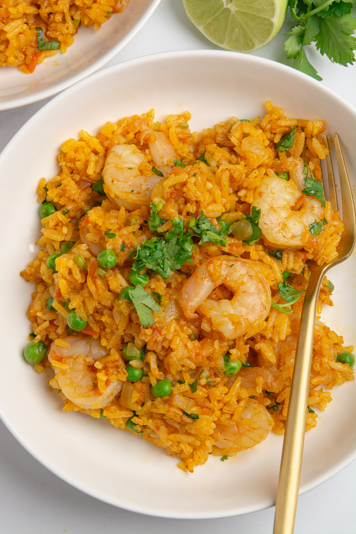 A dish with shrimp, rice, peas, and cilantro with a fork on the side.