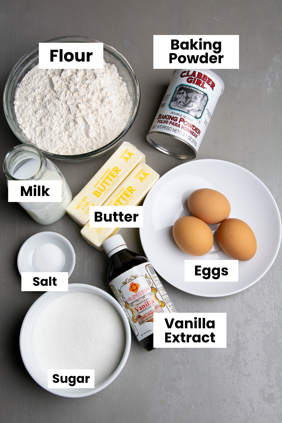 Ingredients for pound cake, flour, baking powder, milk, butter, eggs, salt, sugar, vanilla extract.