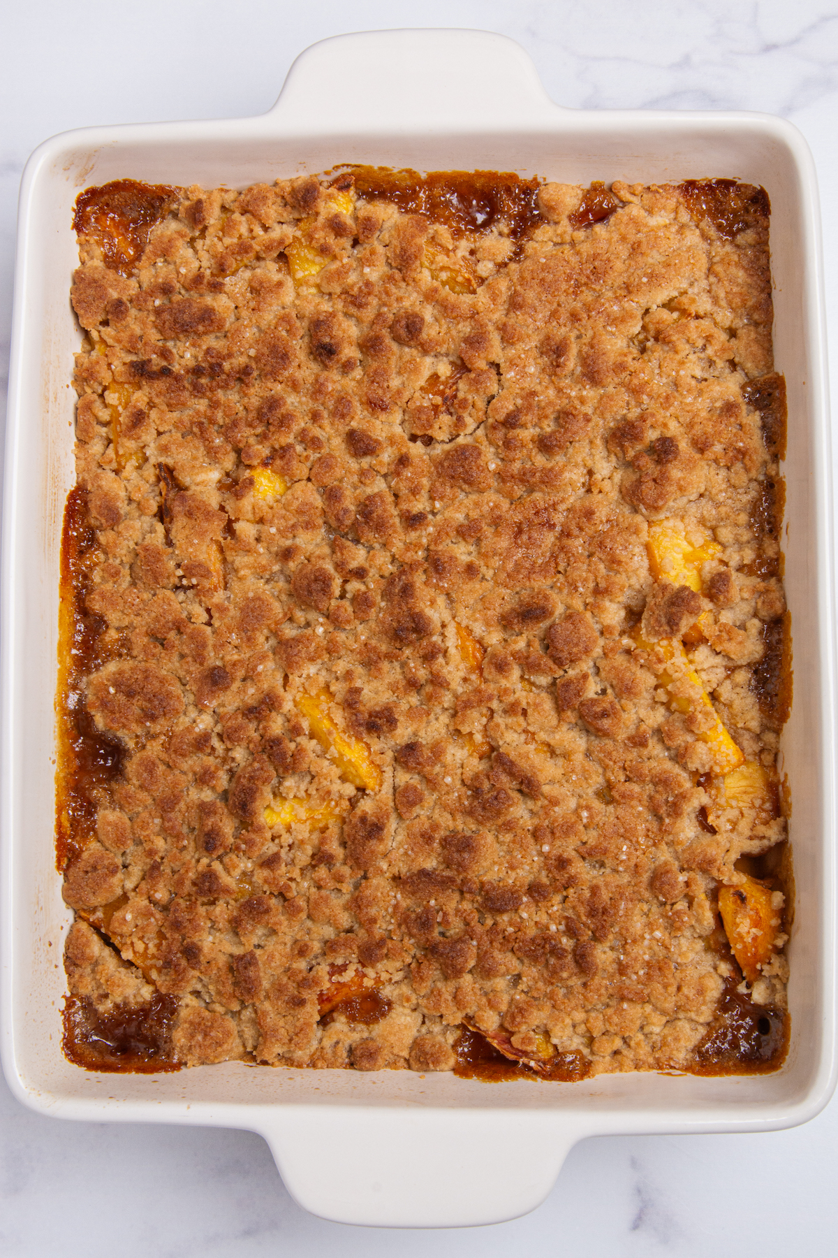 A baking pan filled with baked peach cobbler with a golden brown topping.