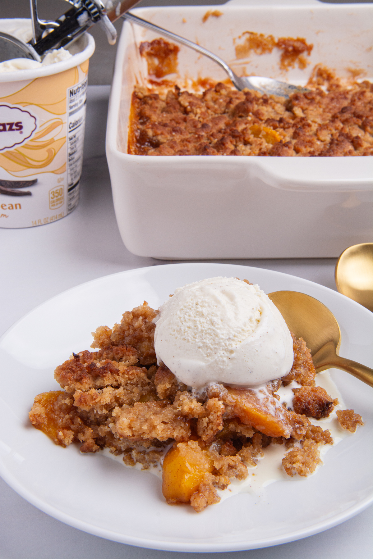 A serving of peach cobbler topped with a scoop of vanilla ice cream.