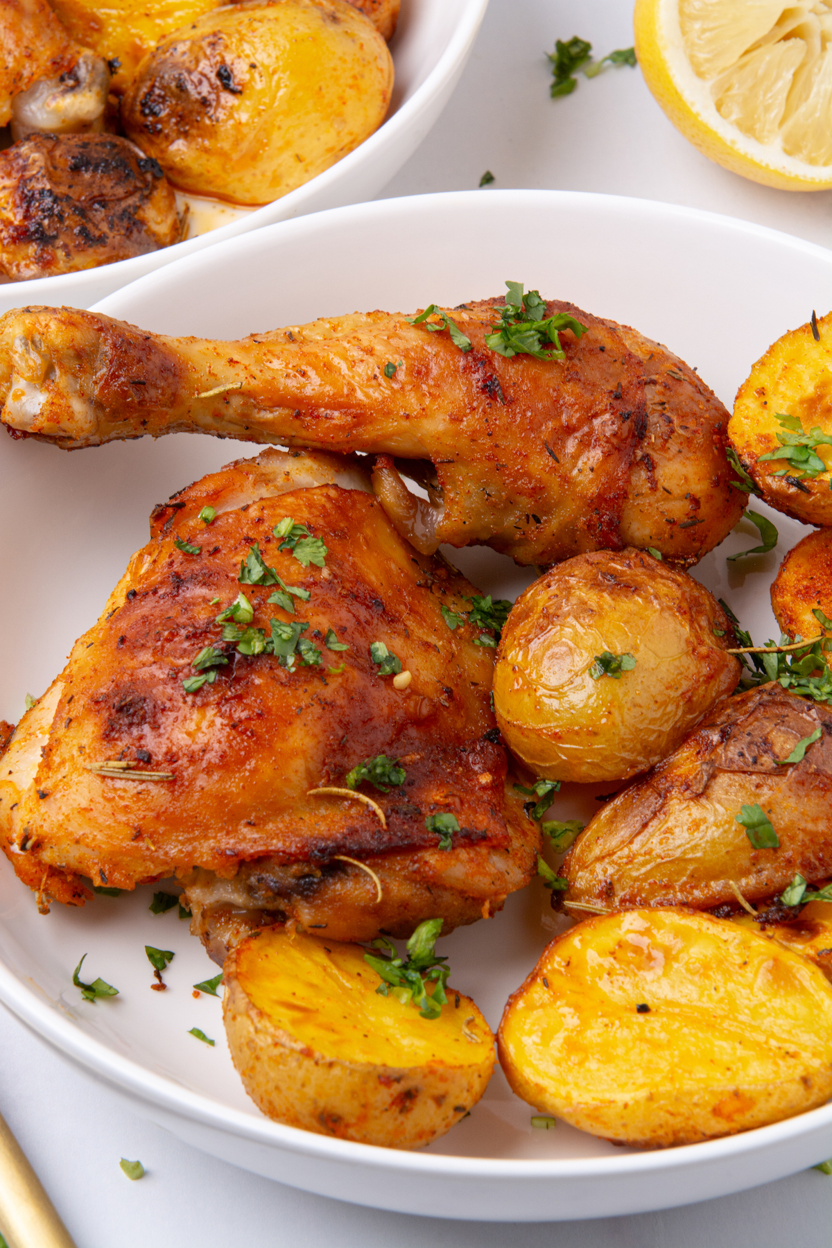 A plate with roasted a roasted chicken leg and thigh and potatoes.