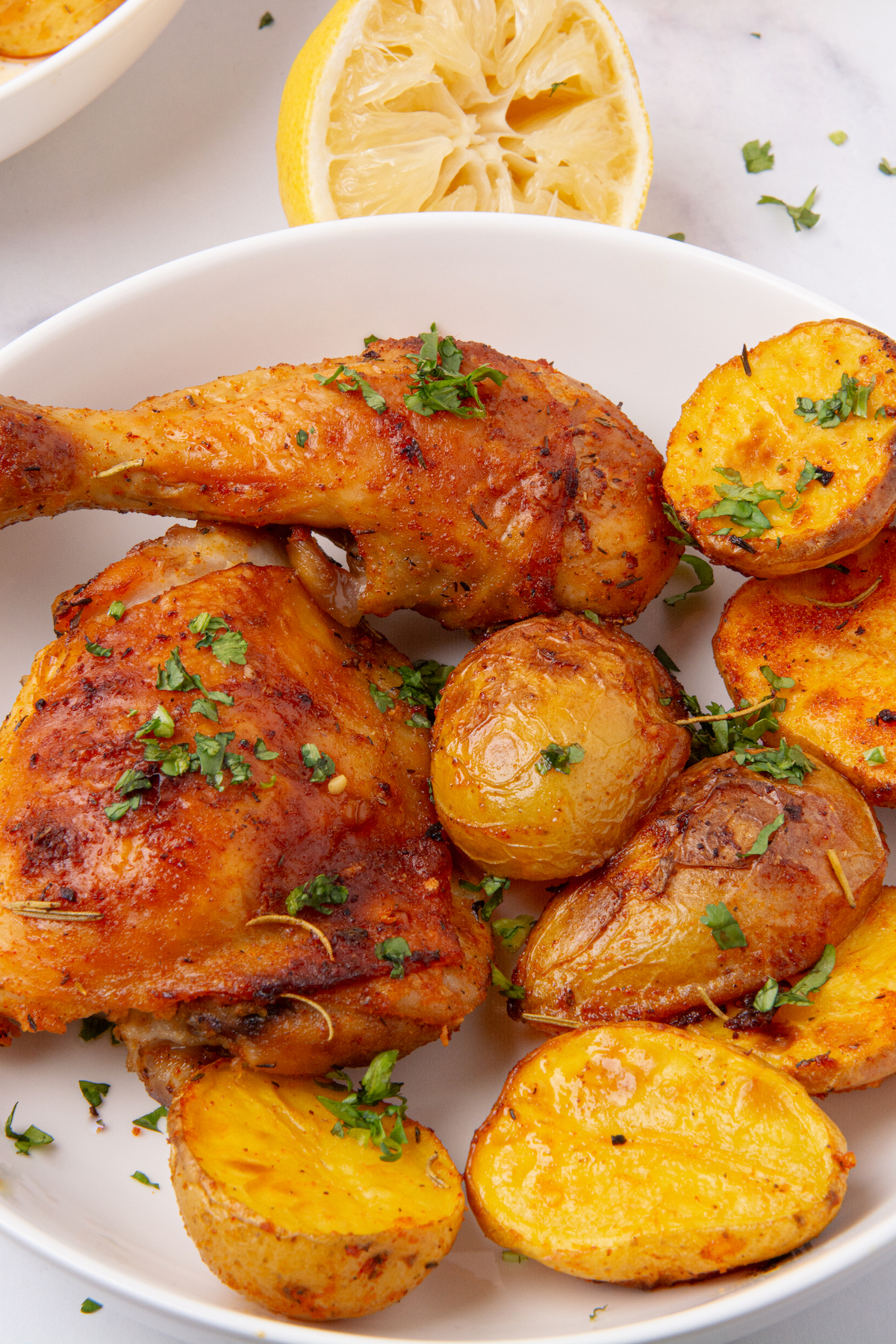 A plate with roasted a roasted chicken leg and thigh and potatoes.