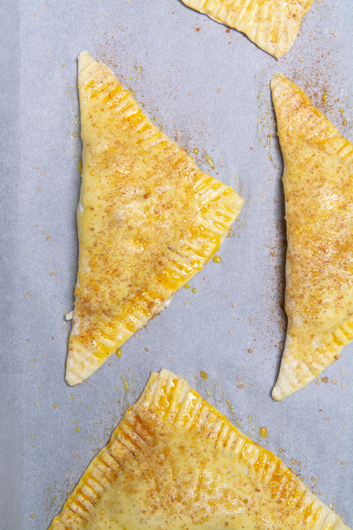 Unbaked apple turnovers on a baking sheet.