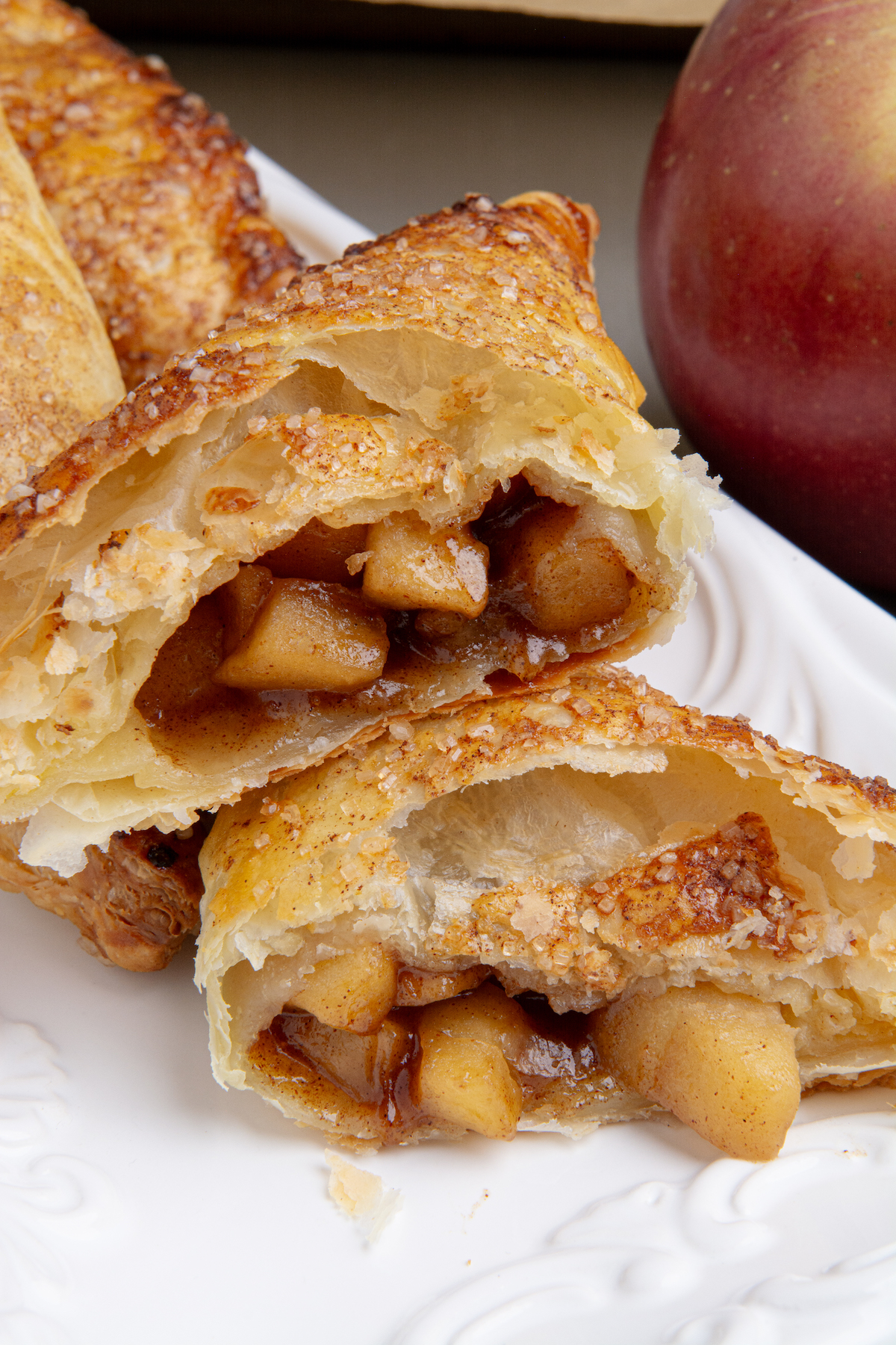 A baked and golden brown apple turnover cut in half showing a delicious caramel apple filling.