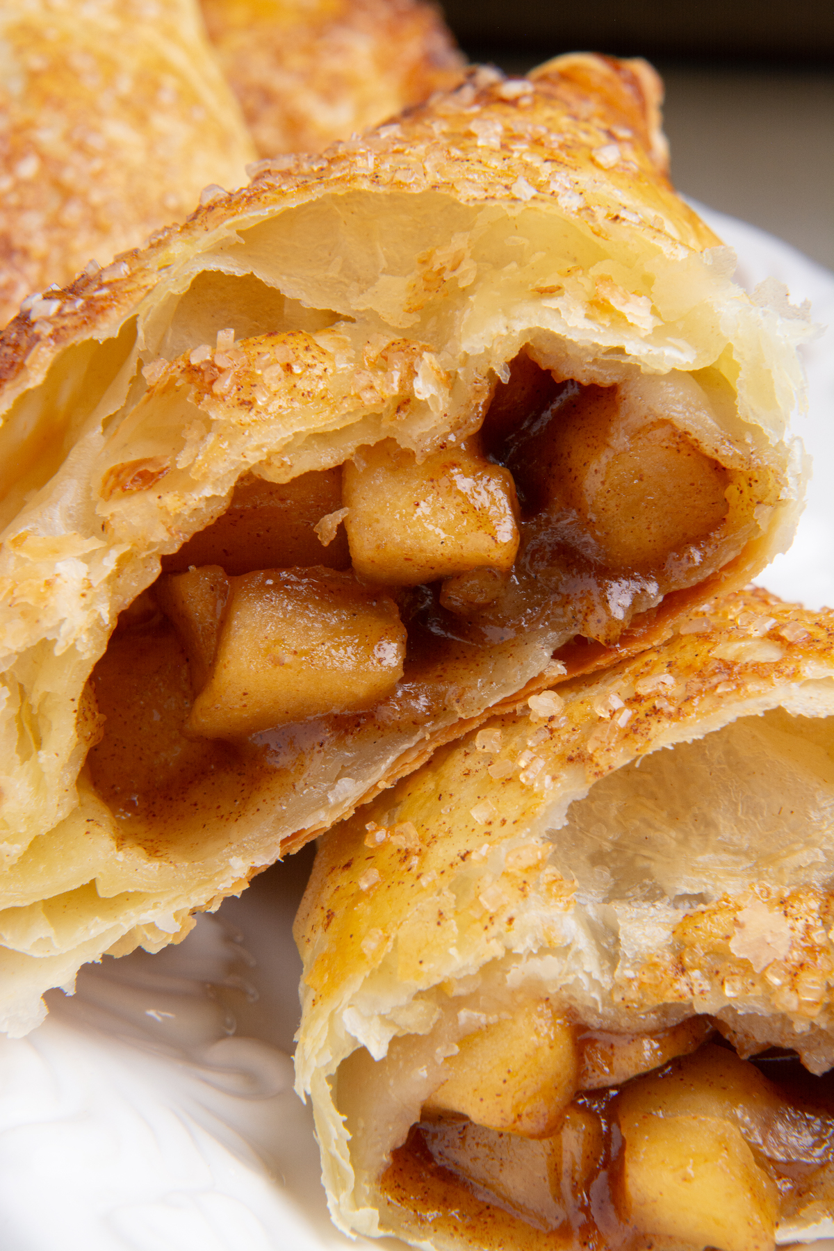 An baked and golden brown apple turnover cut in half showing a delicious caramel apple filling.