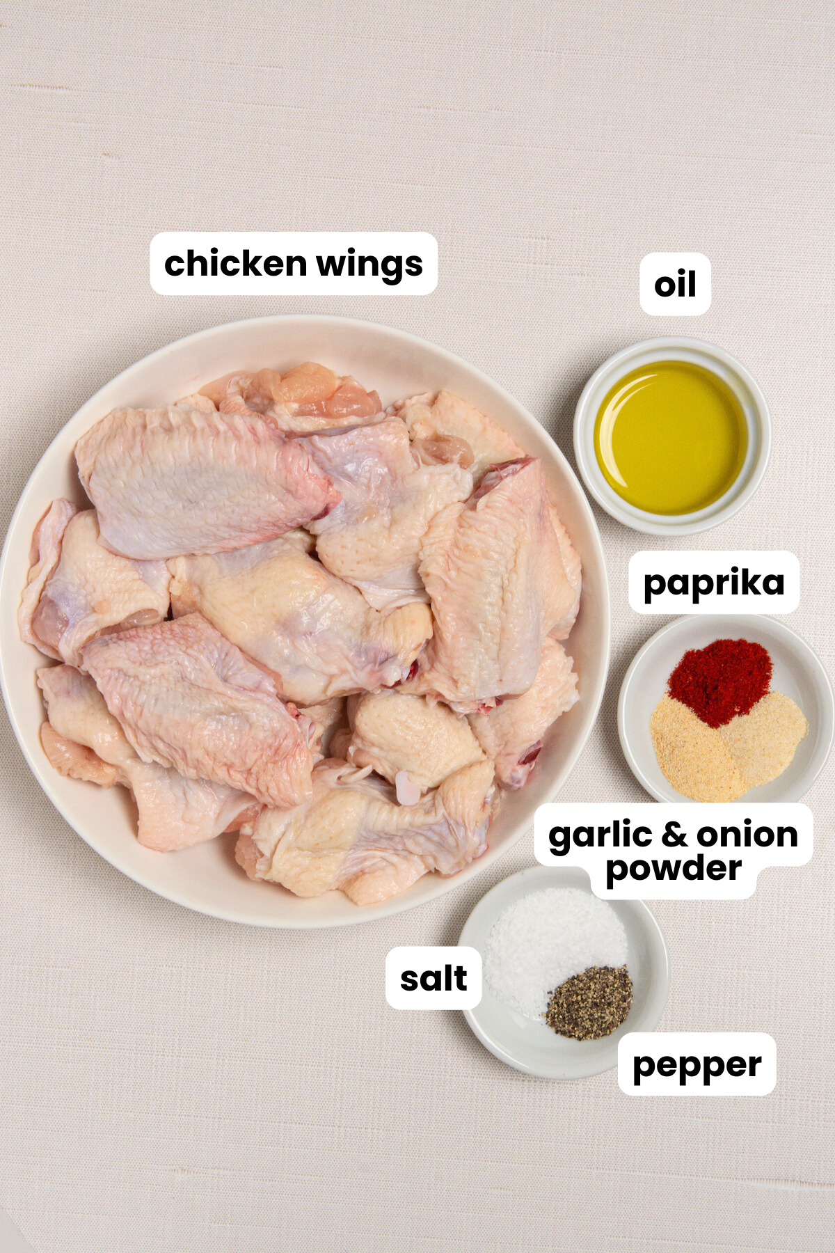 Ingredients for making air fryer chicken wings, chicken wing flats and drums, oil, paprika, garlic powder, onion powder, salt, and pepper.