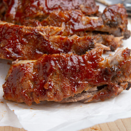 Instant pot baby back ribs smothered in BBQ sauce cut into individual ribs.