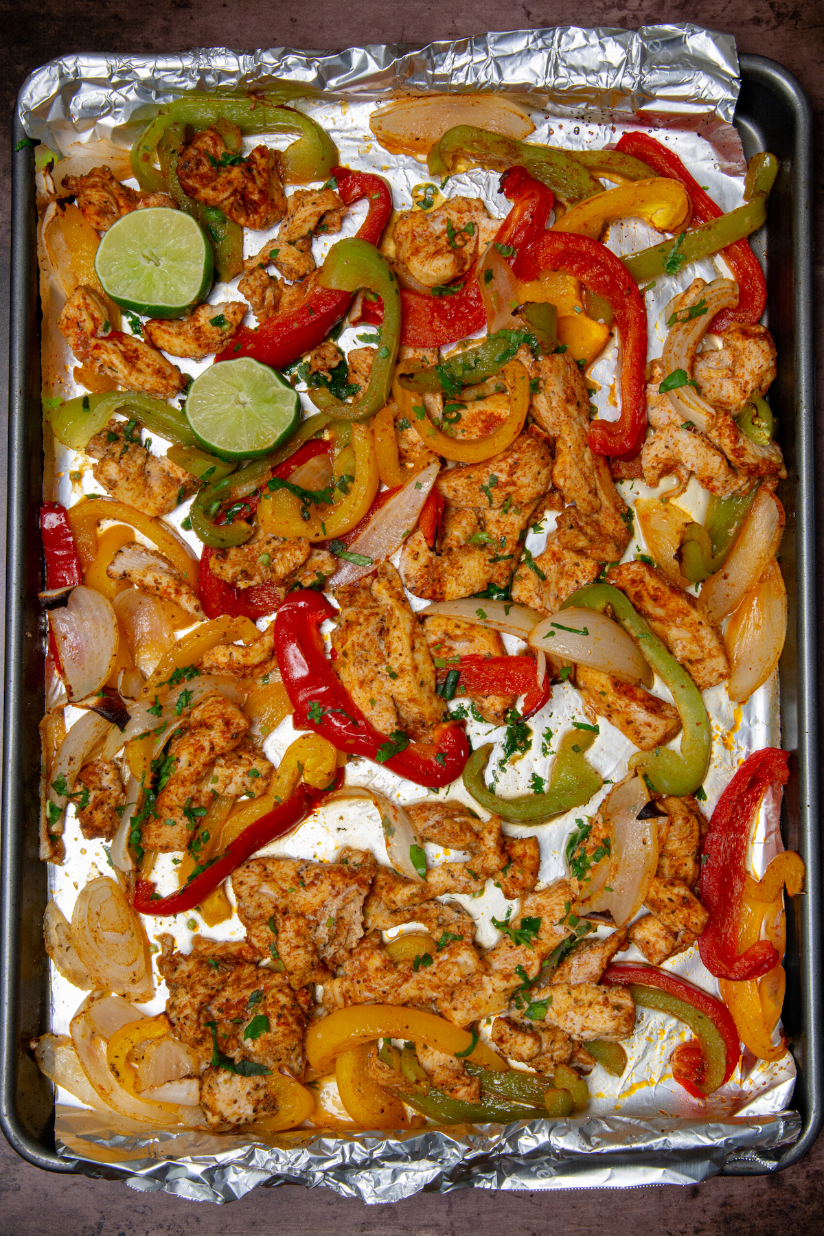 A baking sheet with cooked chicken fajitas.