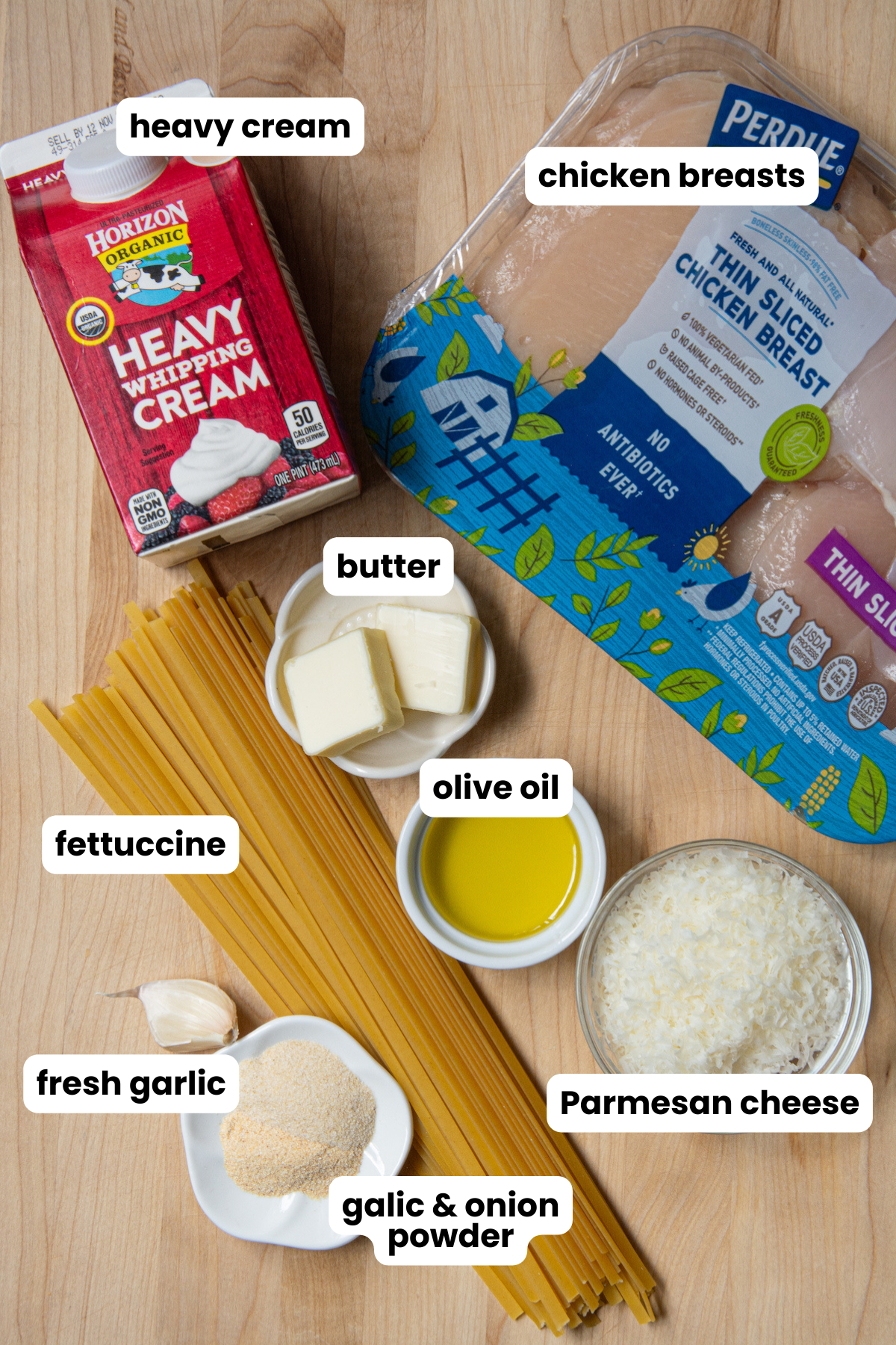 Ingredients for a chicken Alfredo with fettuccine, which include fettuccine pasta, chicken breasts, garlic powder, onion powder, fresh garlic, butter, olive oil, heavy cream and grated Parmesan cheese.