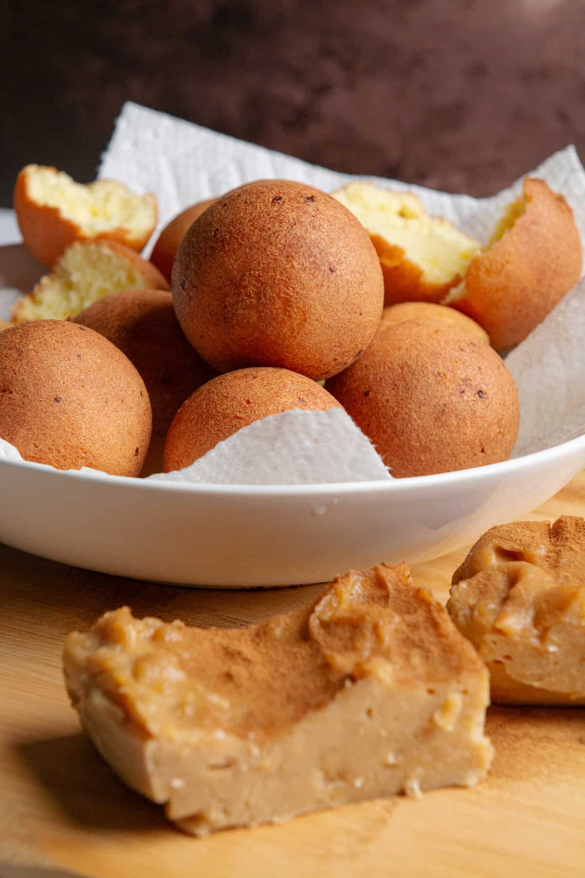 A stack of golden brown Colombian buñuelos with Colombian natilla.