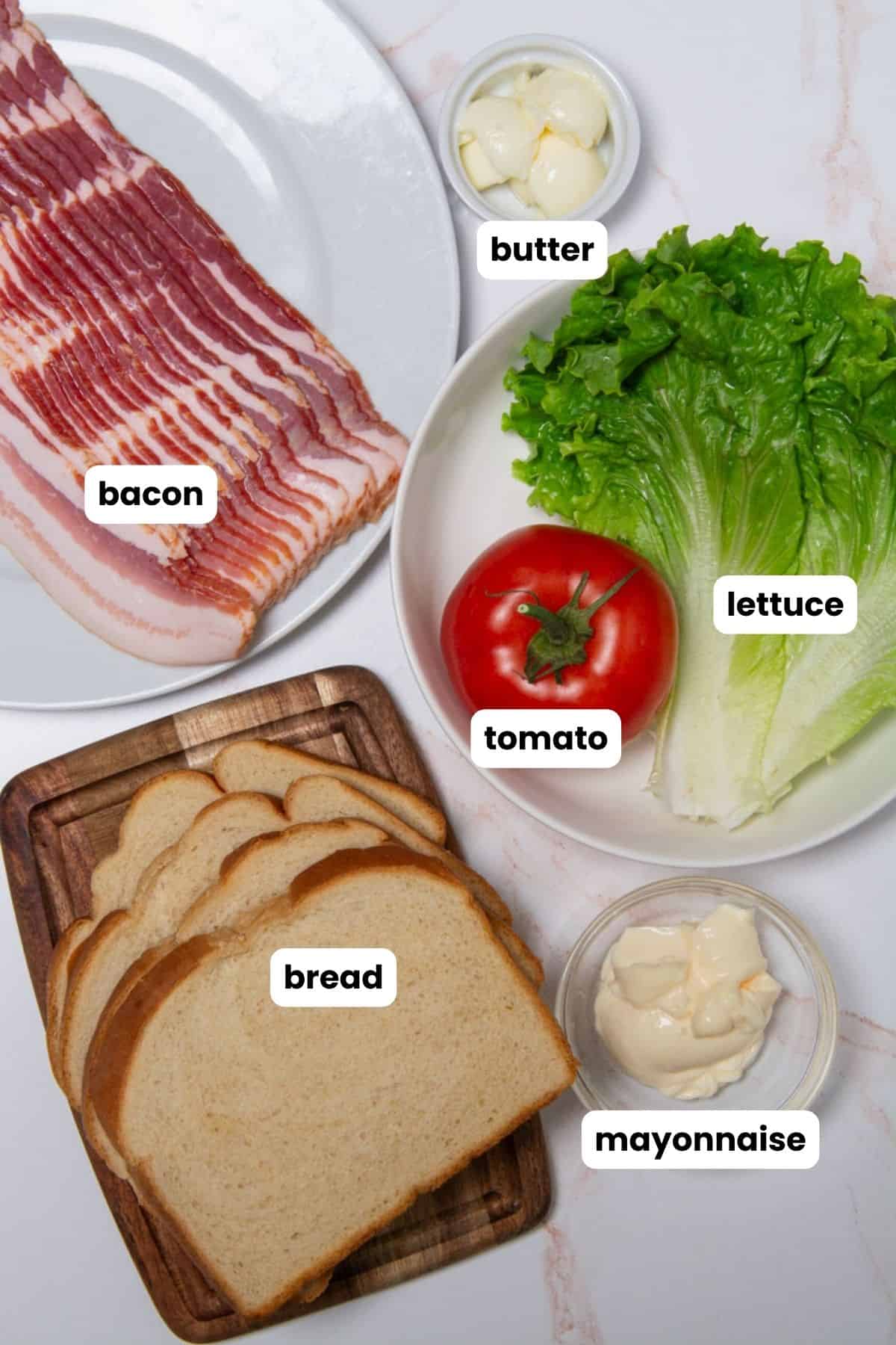 Ingredients for a BLT sandwich, bacon, lettuce, tomato, bread, butter, and mayonnaise.