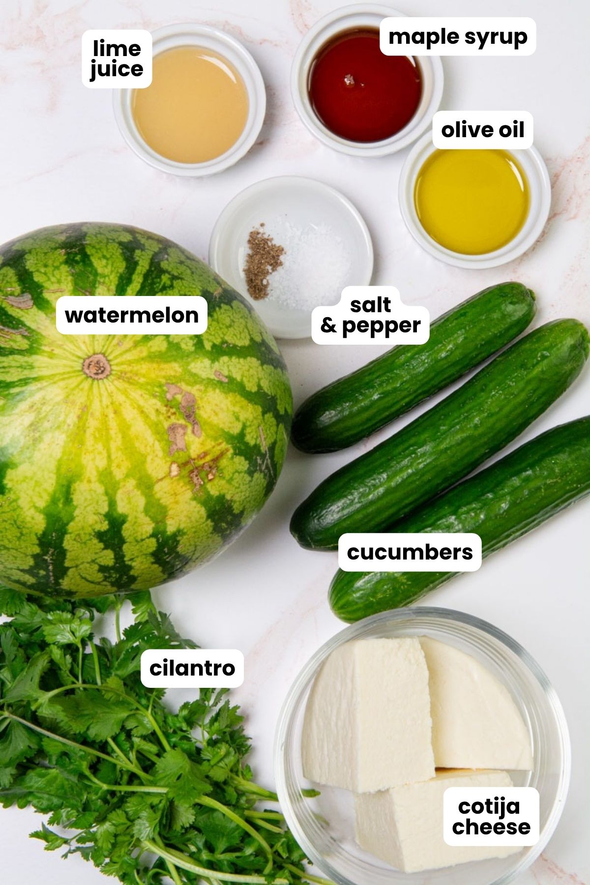 List of ingredients for a watermelon cucumber salad which include watermelon, cucumbers, cilantro, cotija cheese, maple syrup, lime juice, olive oil, salt, and pepper.