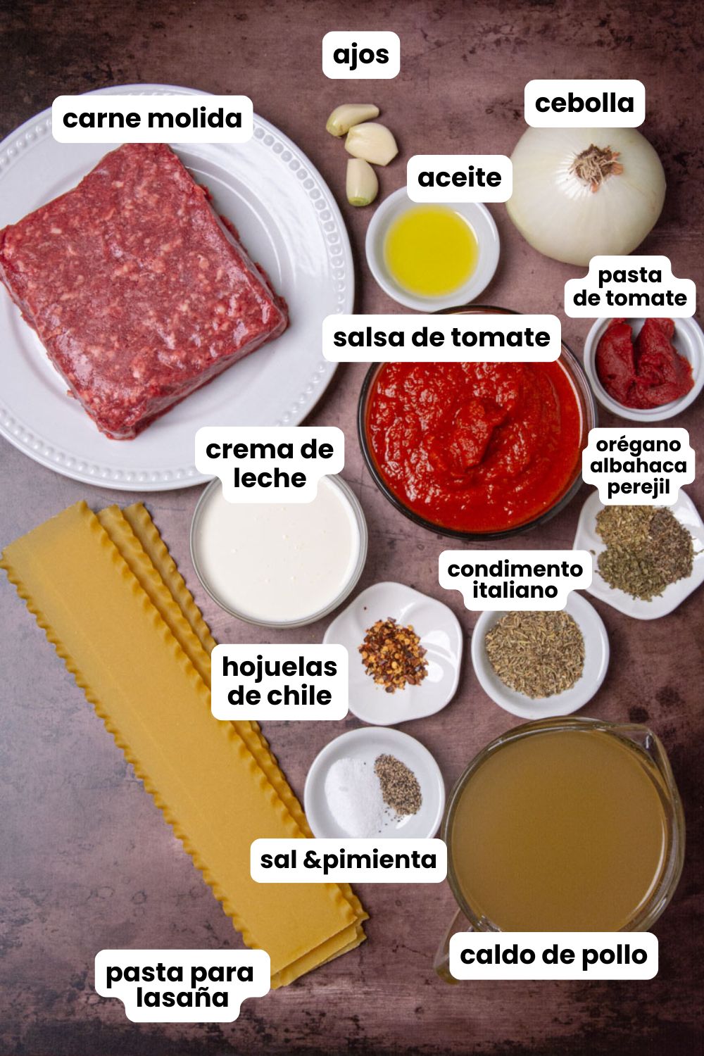 Ingredients in Spanish for lasagna soup which include oil, onion, garlic, ground beef, tomato sauce, tomato paste, Italian seasoning, dry oregano, dry basil, dry parsley, chili flakes, chicken broth, heavy cream, lasagna noodles, salt, and black pepper.