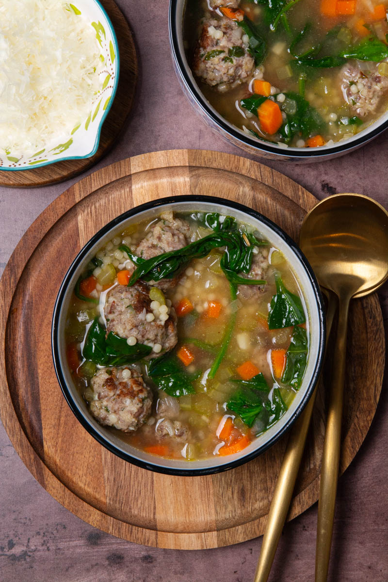 A bowl of Italian Wedding Soup with seared Italian meatballs, broth, spinach, onion, celery, carrots, and ancini di pepe pasta.