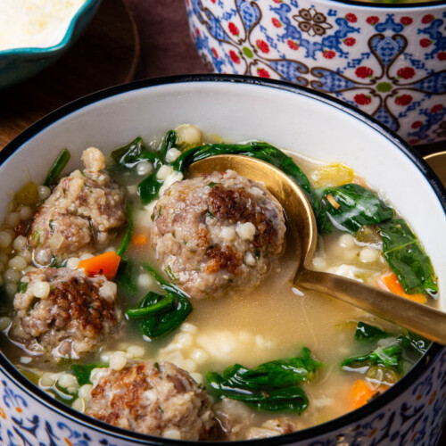 A bowl of Italian Wedding Soup with seared Italian meatballs, broth, spinach, onion, celery, carrots, and ancini di pepe pasta.