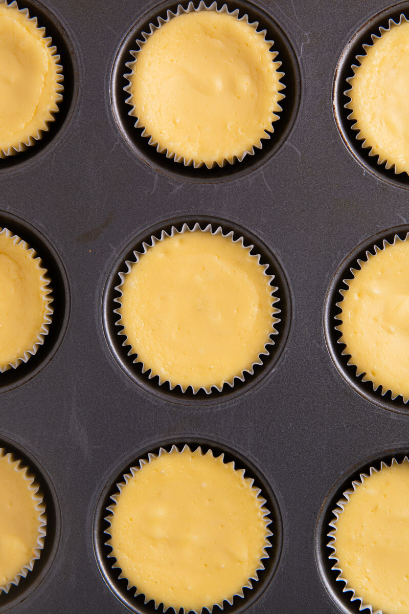 A cupcake tray with baked mini cheesecakes