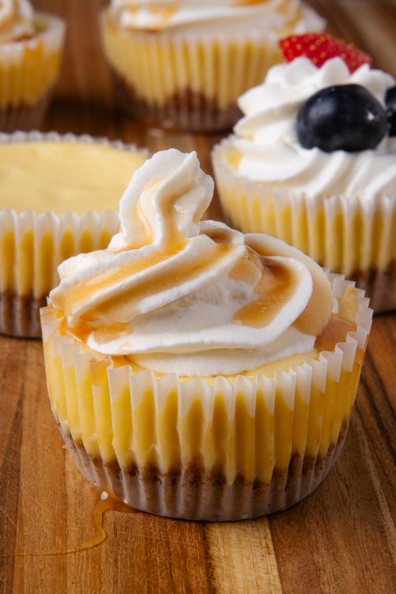 A mini cheesecake topped with whipped cream and drizzled with salted caramel