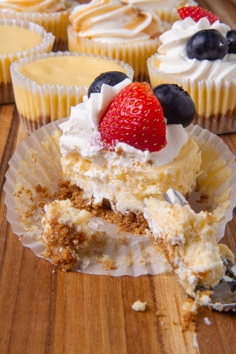 A mini cheesecake topped with whipped cream, blueberries, and one strawberry cut in half