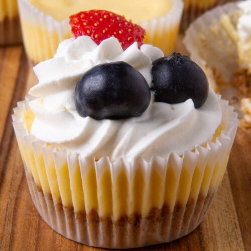 A mini cheesecake topped with whipped cream, blueberries, and one strawberry