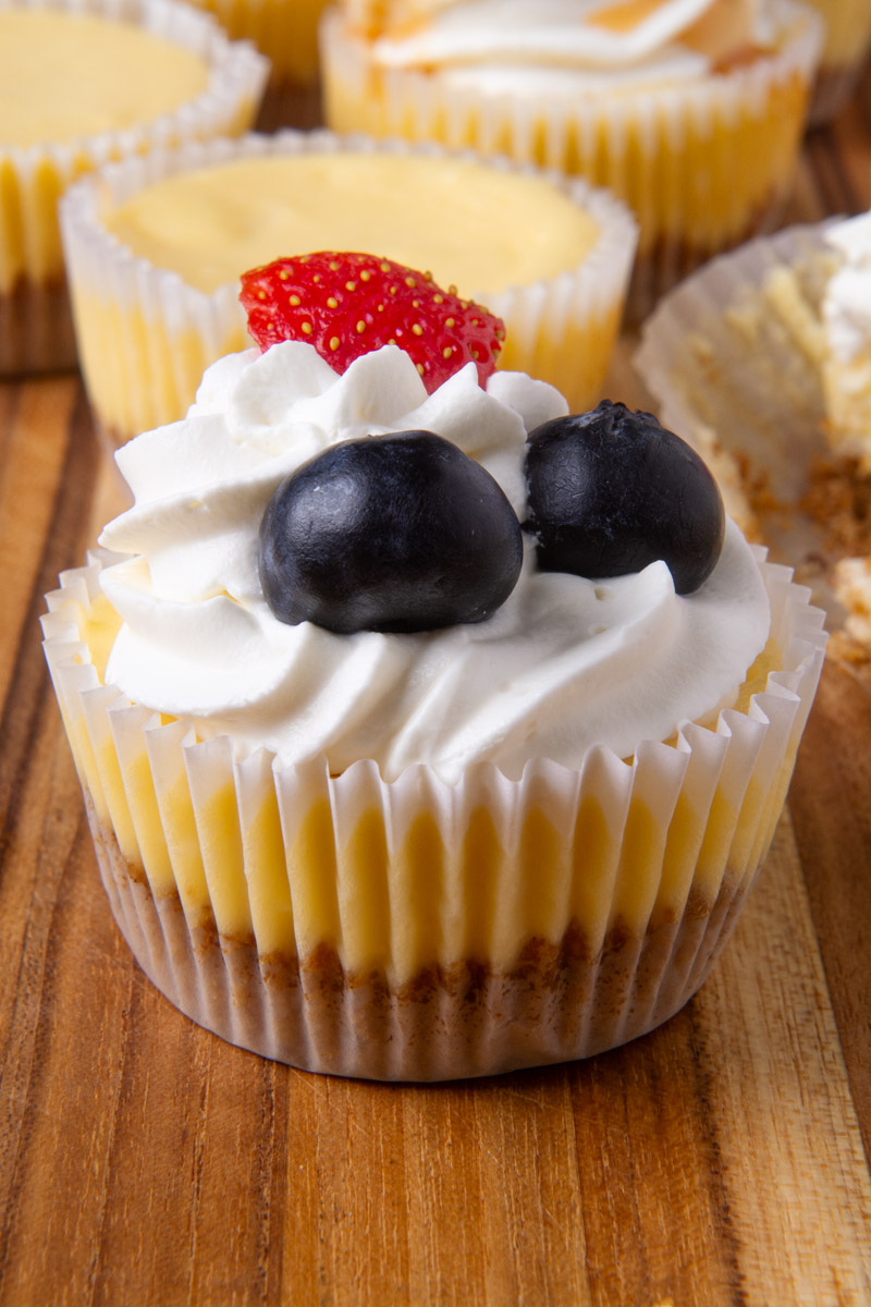 A mini cheesecake topped with whipped cream, blueberries, and one strawberry