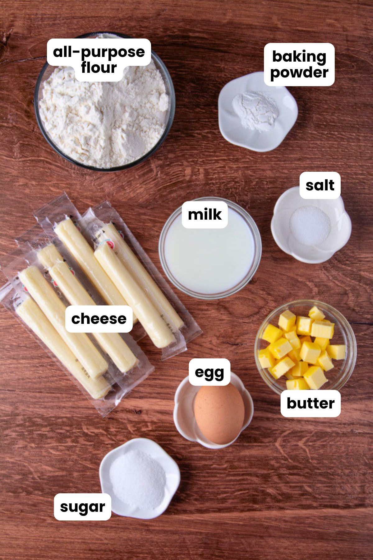 List of Ingredients for making Colombian palitos de queso (cheese sticks) or tequeños which include, all-purpose flour, baking powder, salt, sugar, one egg, milk, cold butter cut into cubes, and string cheese.
